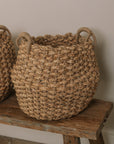 Jute woven basket with handles and a muslin blanket.