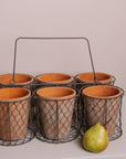 Clay herb pots in wire basket with a pear.