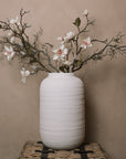 Ceramic large white textured vase with magnolia flowers and branches.