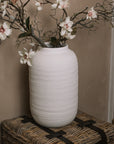 Ceramic large white textured vase with magnolia flowers and branches.