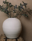 Ceramic round white textured vase with berry sprays and branches.