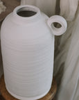 Textured White Vase with berry spray on wooden stool.