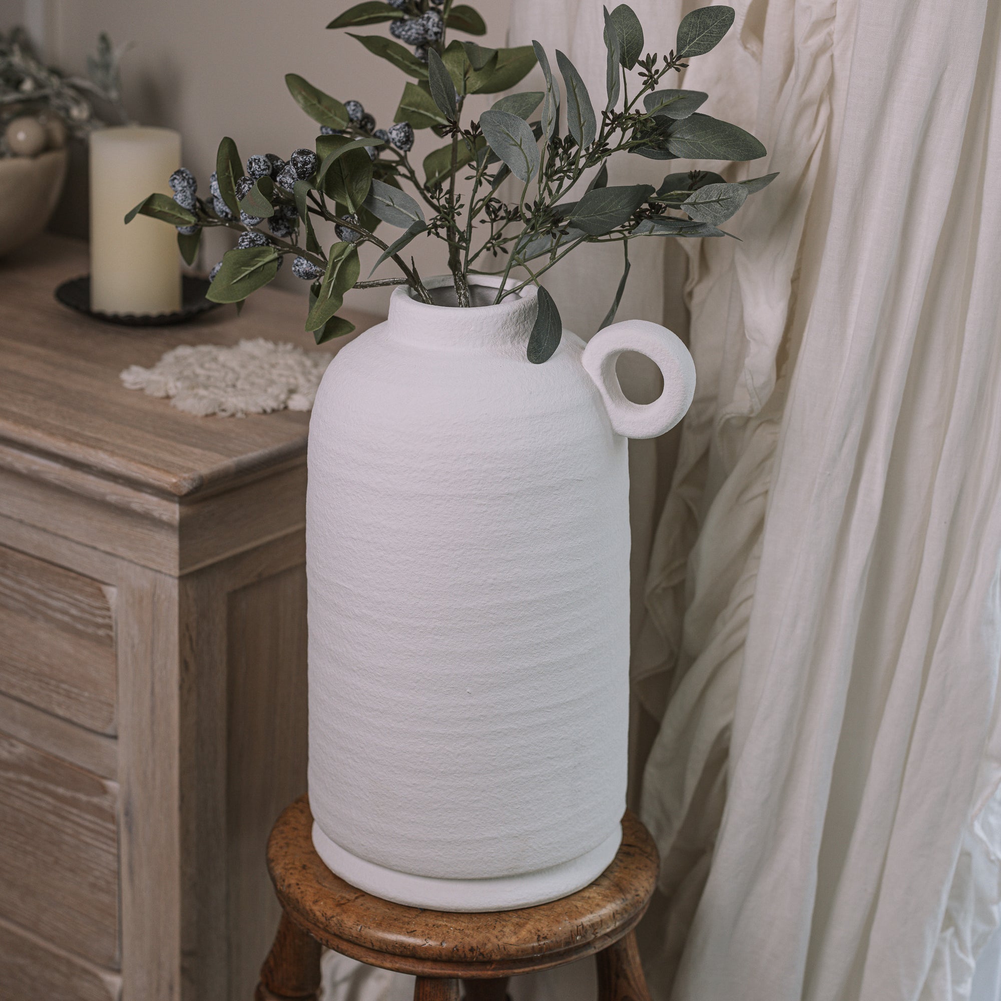 Textured White Vase with berry spray on wooden stool.