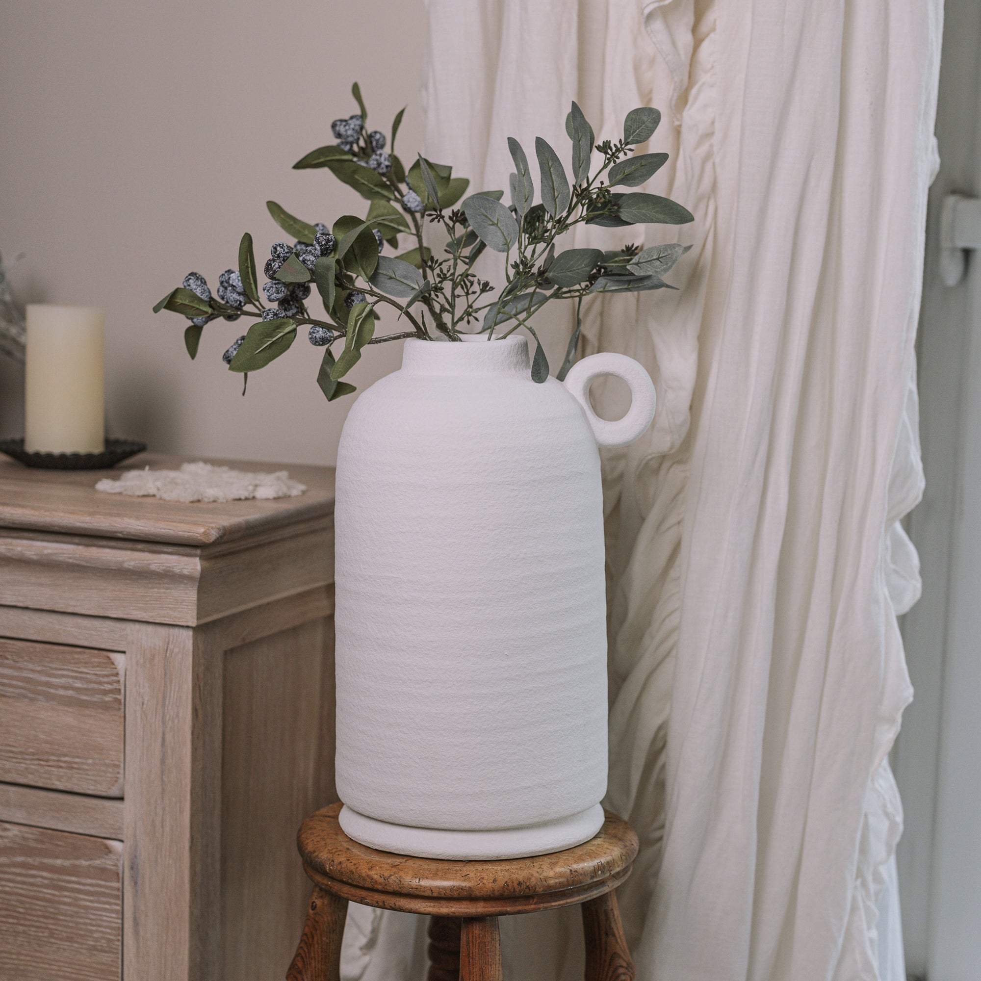 Textured White Vase with berry spray on wooden stool.