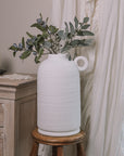 Textured White Vase with berry spray on wooden stool.