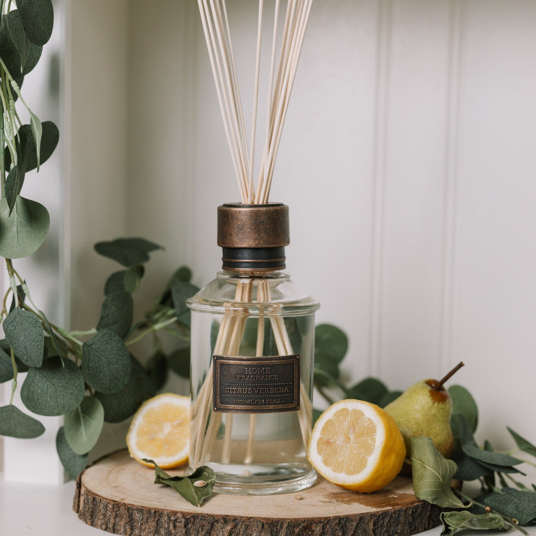 Home fragrance citrus verbena reed diffuser with lemons and greenery.