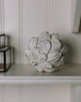Distressed Artichoke Ornament on a white shelf.