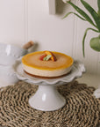 Small white ceramic cake stand with pie crust edge.
