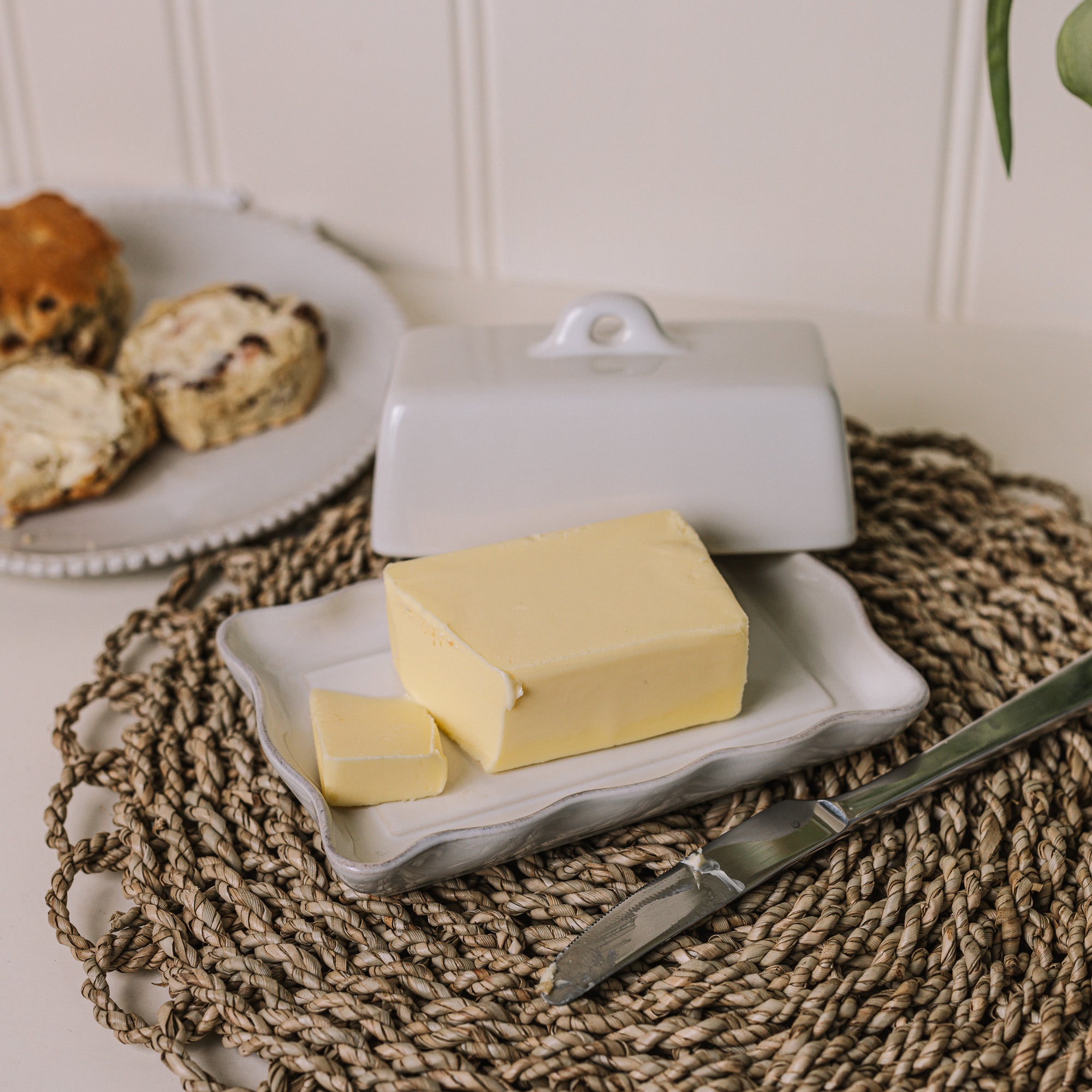 White stoneware butter dish with lid and pie crust edge with a block of butter..