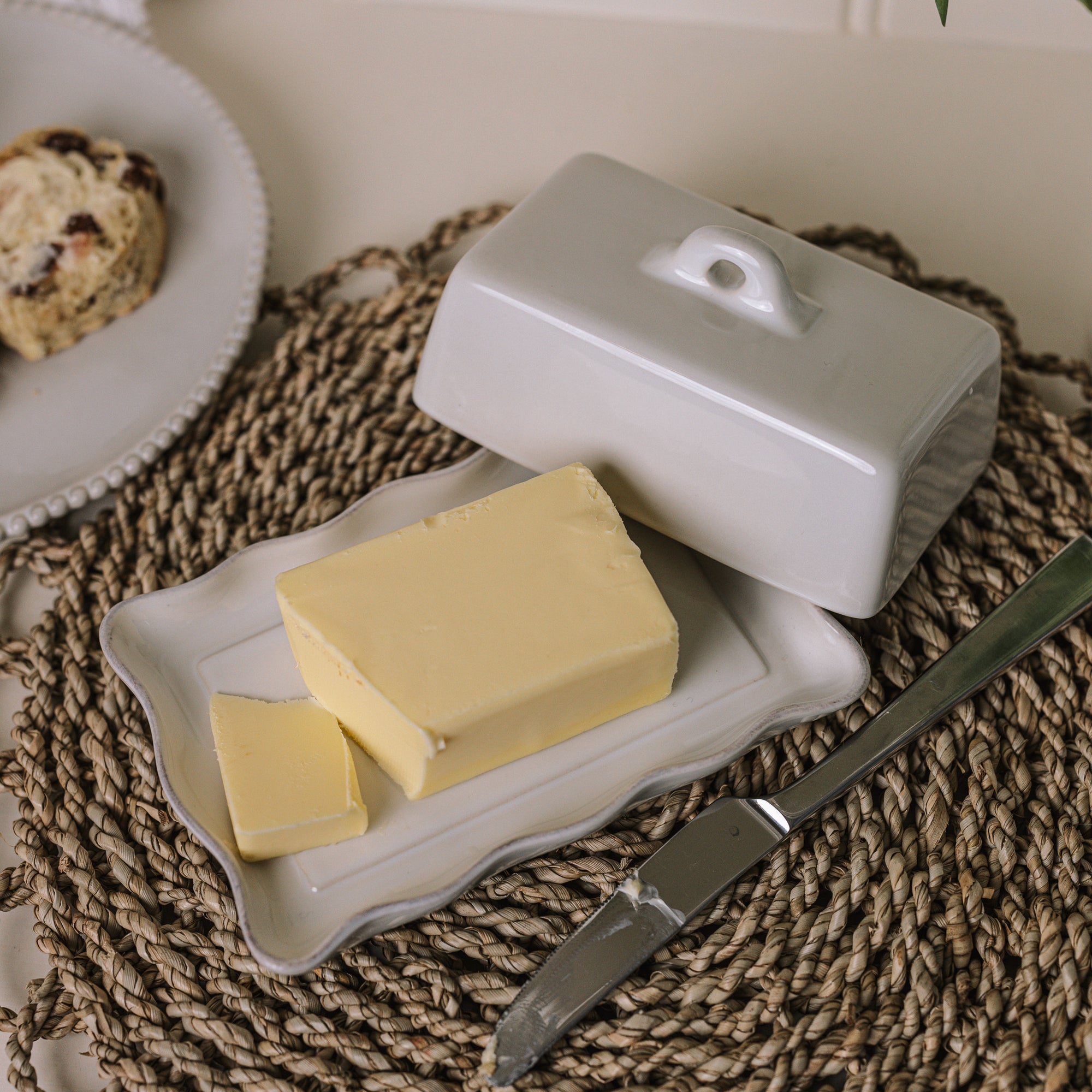 White stoneware butter dish with lid and pie crust edge with a block of butter..