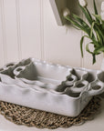 Stack of white baking dishes with handles and pie crust edge.