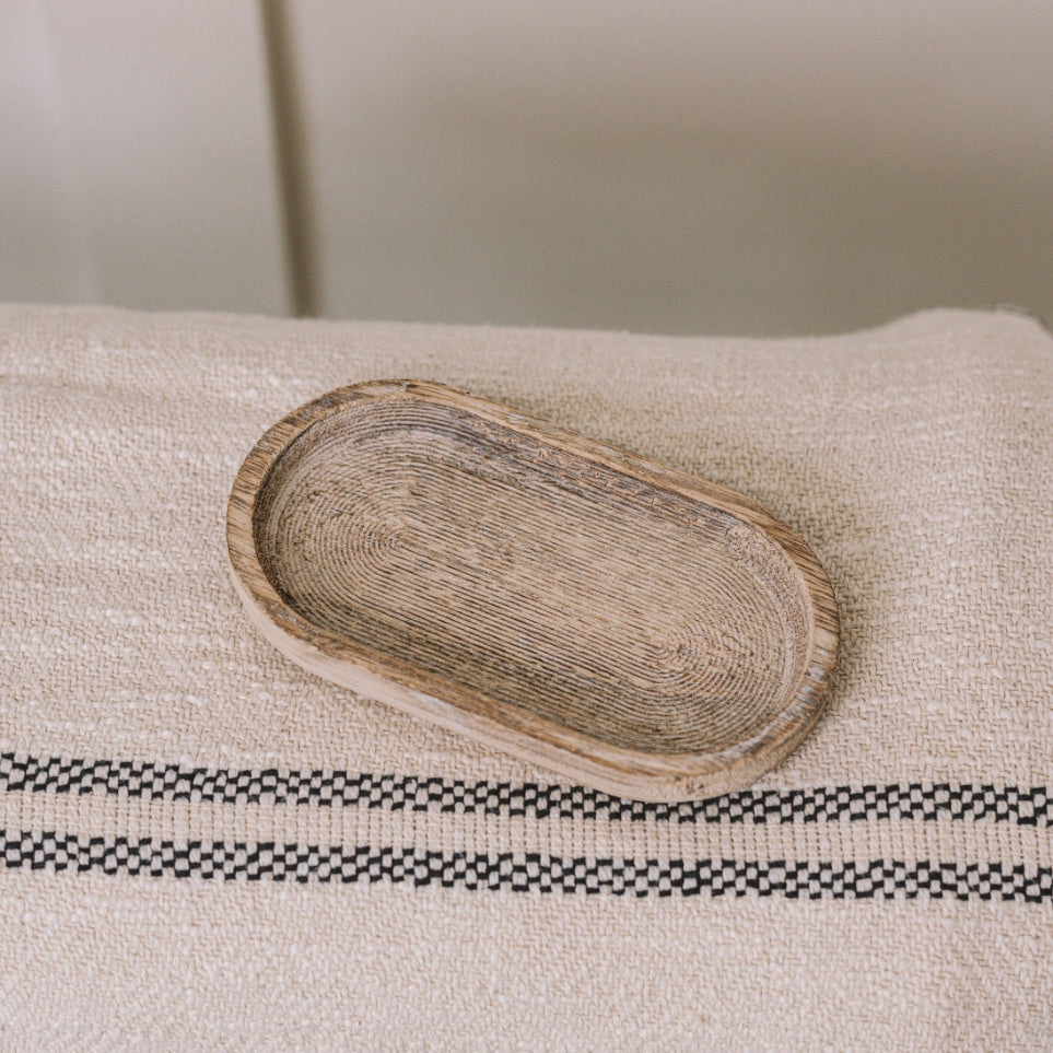 Small rustic wooden tray on cream throw.