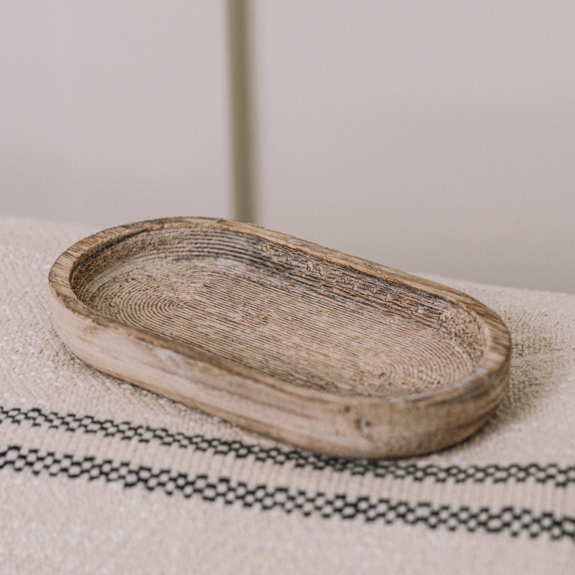 Small rustic wooden tray on cream throw.