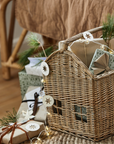 Woven basket with handle filled with Christmas presents and decorations.