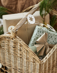 Woven basket with handle filled with Christmas presents and decorations.