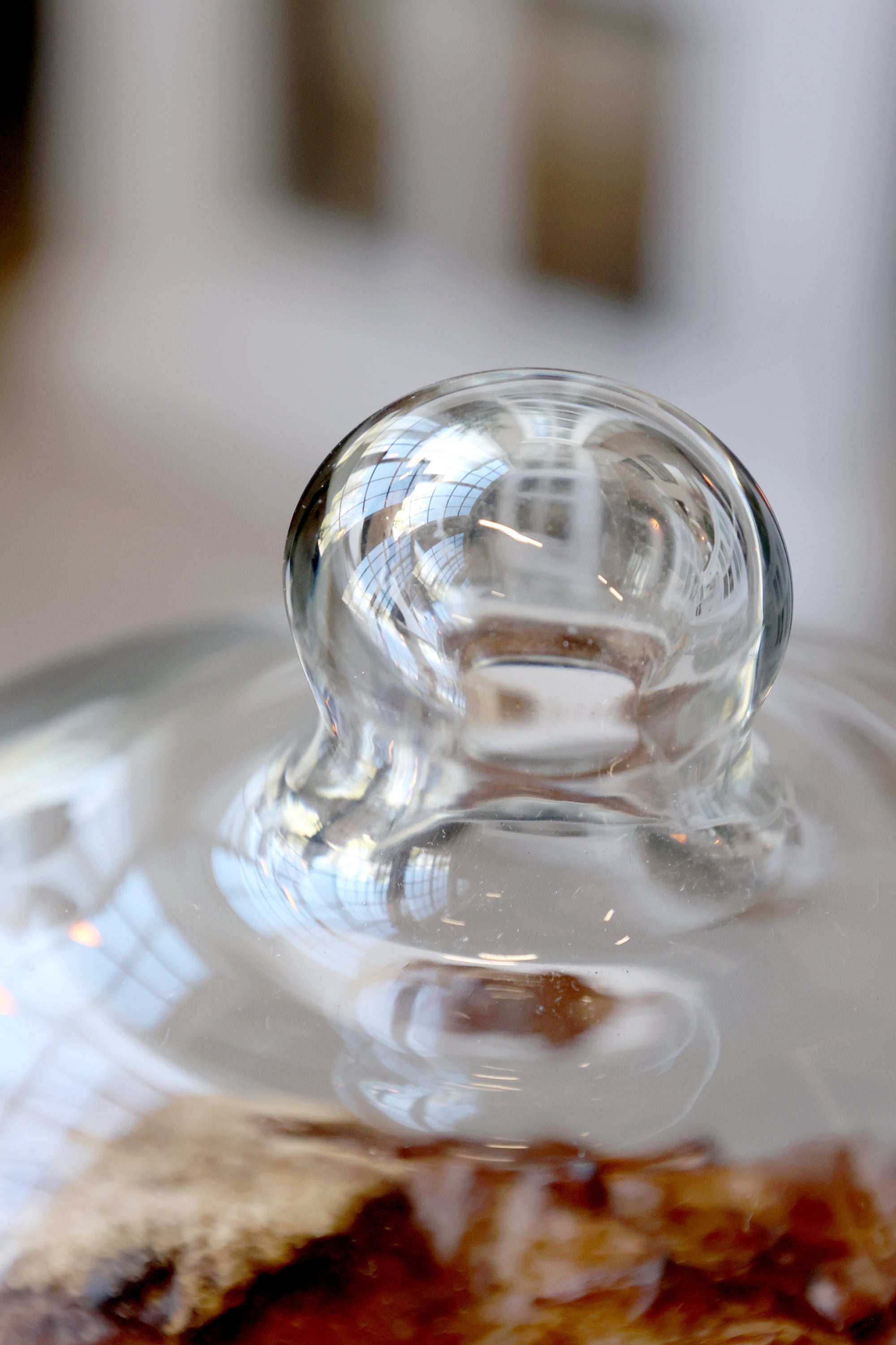 Close up of knob on wood and glass dome.