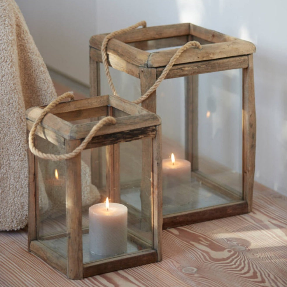 Set of two wooden candle lanterns with lit white candles inside.