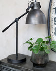 Antique coal desk lamp on desk with plant.