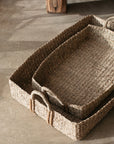 The Eliza Rectangular Seagrass Baskets stacked on a concrete floor.