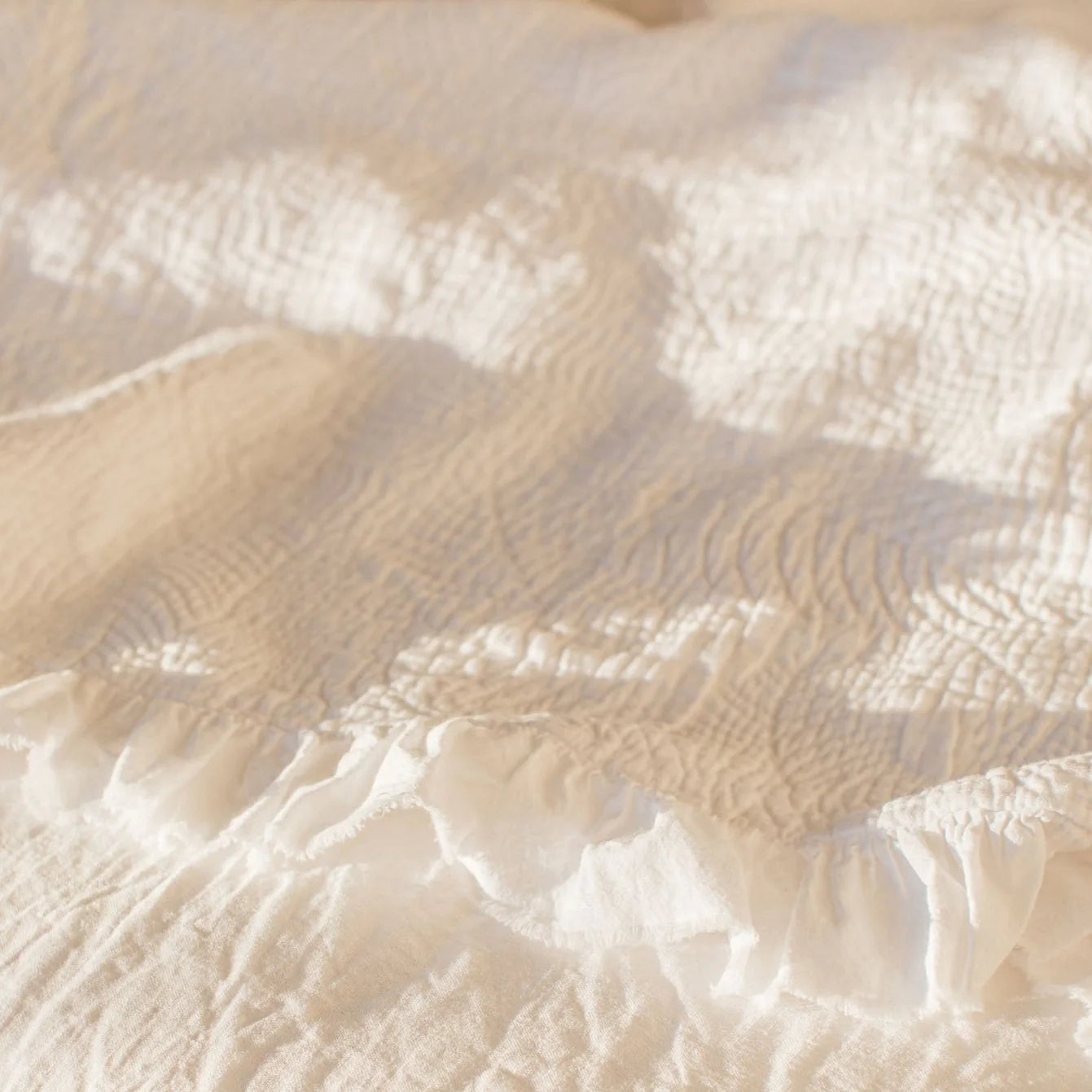 Textured white bedspread in the sunshine.
