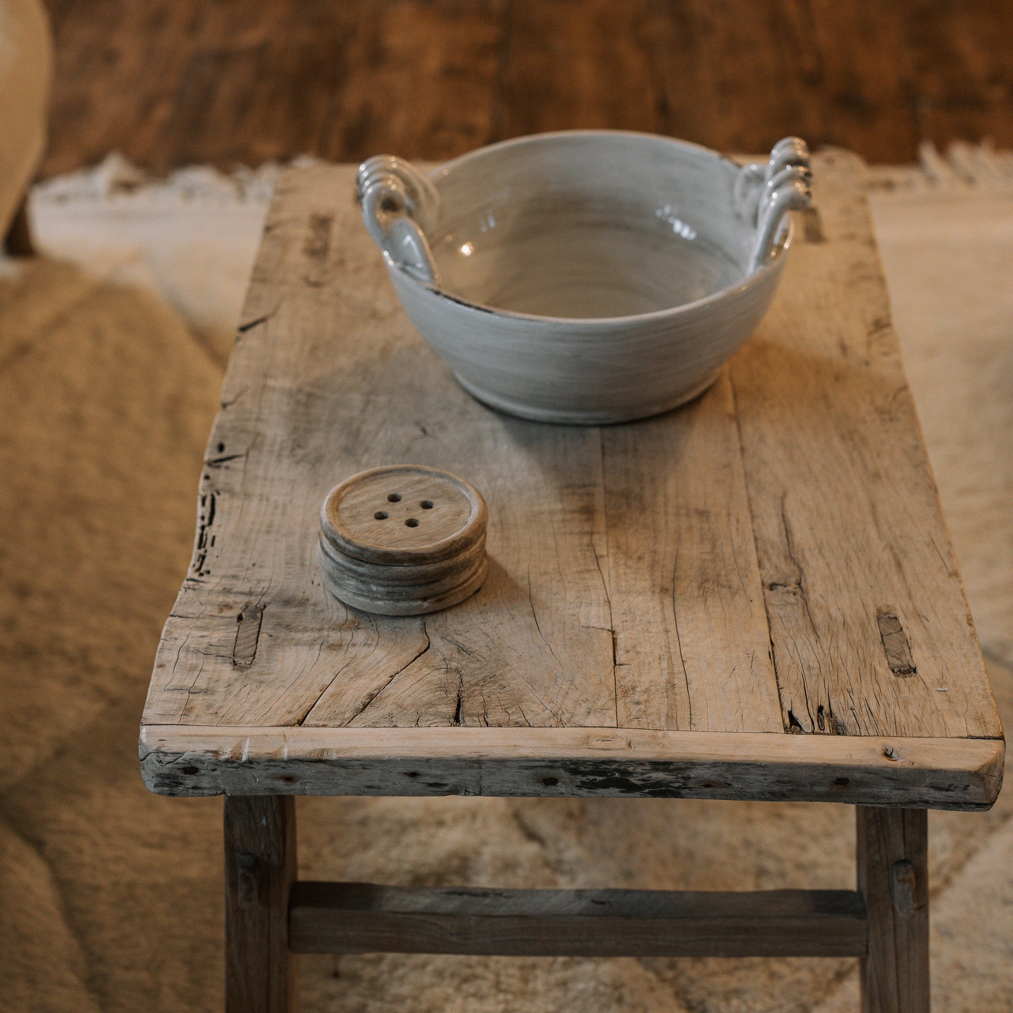 A Reclaimed Wood Coffee Table on white rug with ceramic bowl.