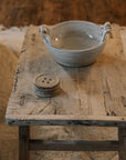 A Reclaimed Wood Coffee Table on white rug with ceramic bowl.