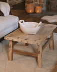 A Reclaimed Wood Coffee Table on white rug with ceramic bowl.