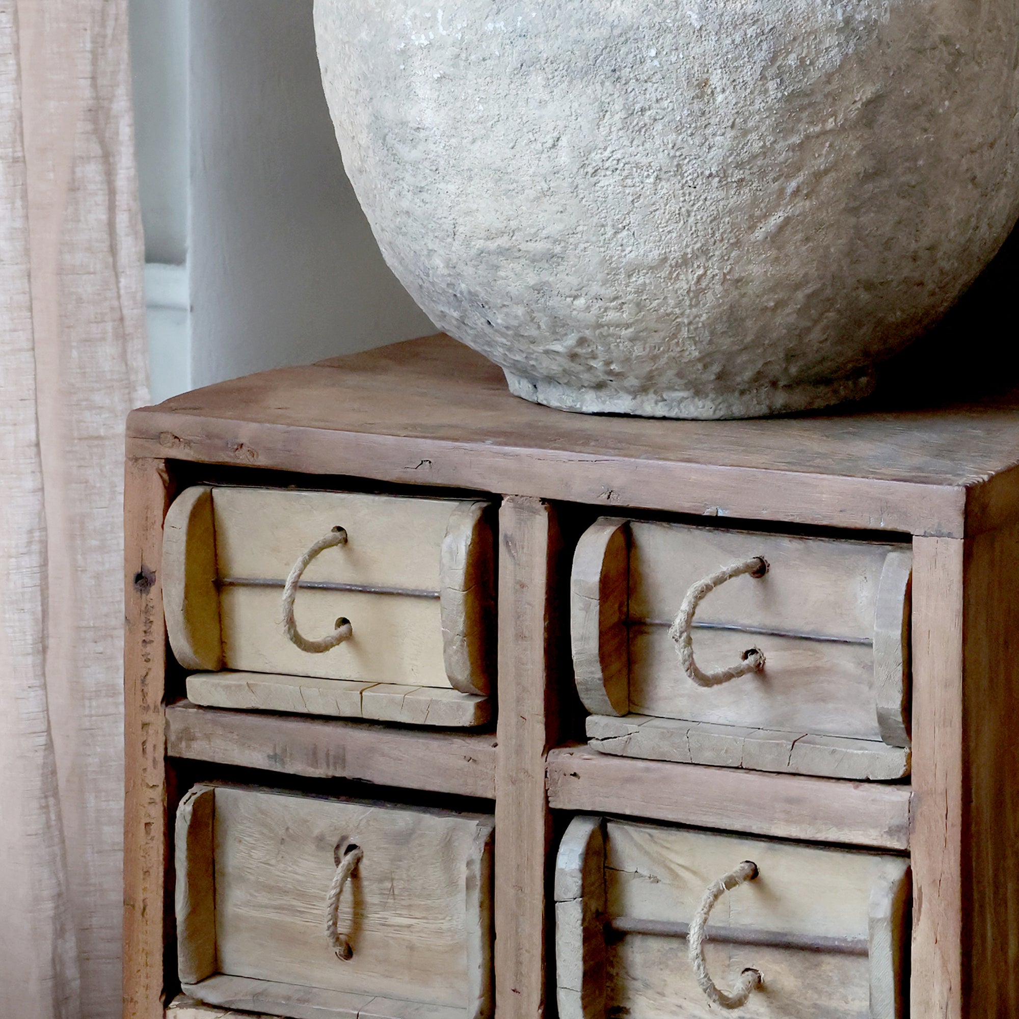 Rustic chest of drawers with large vase on top.