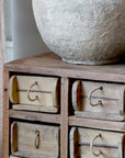 Rustic chest of drawers with large vase on top.