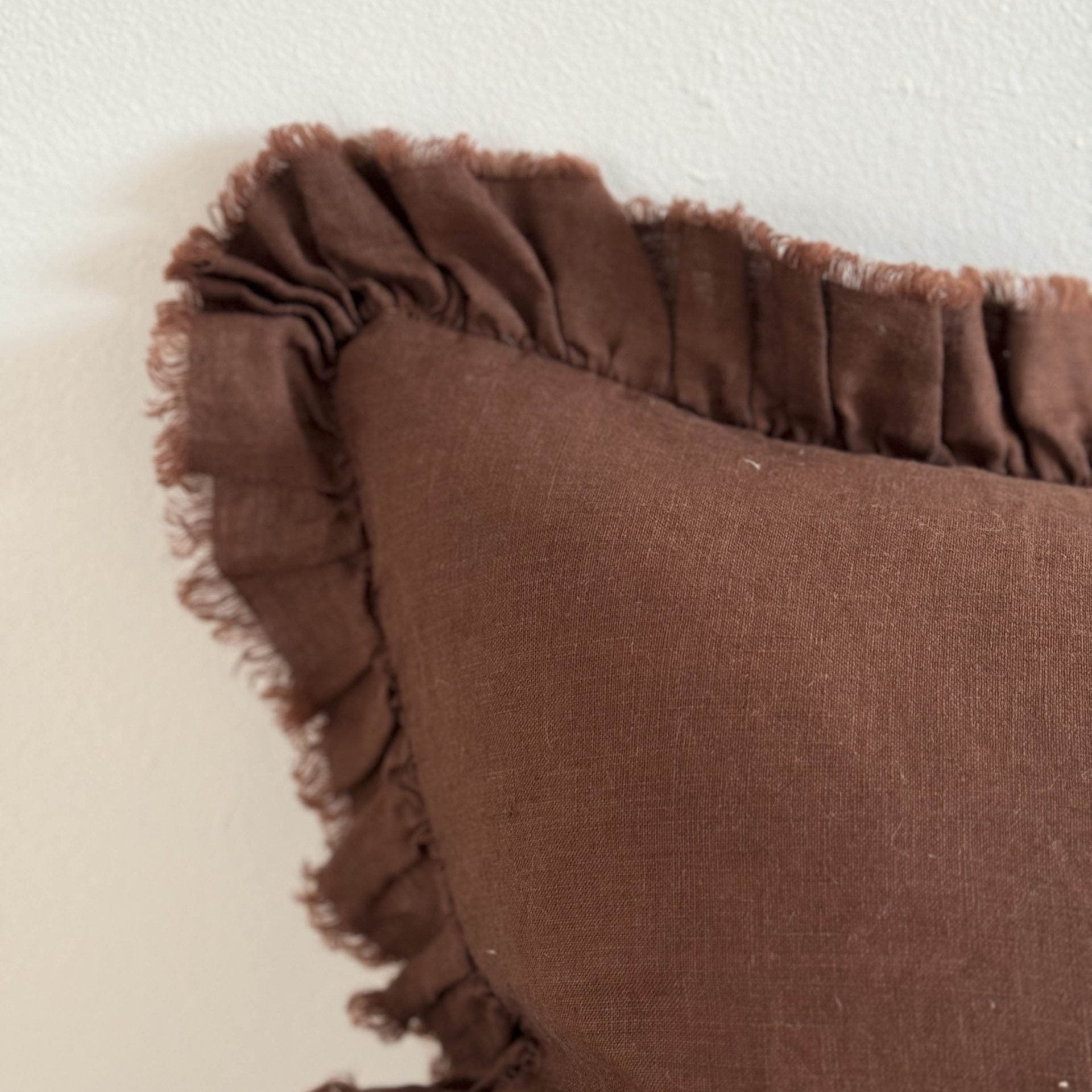 Close up of chocolate brown linen cushion with ruffle edge.