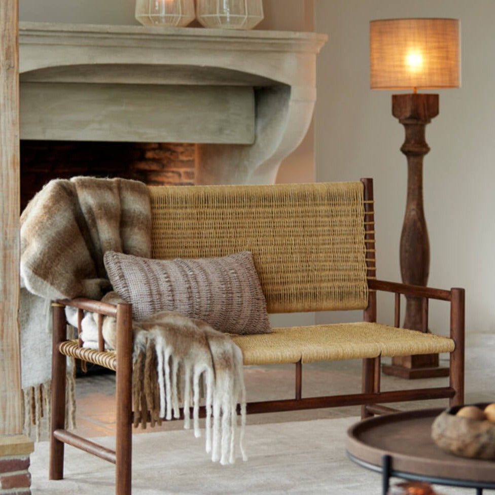Cream and brown throw draped over woven chair.