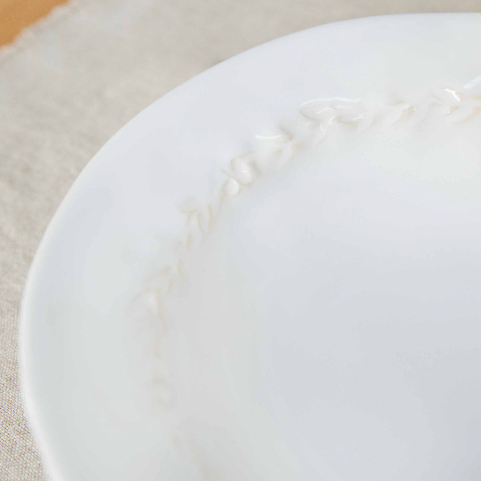 Close up of leaf detailing on white ceramic side plate.