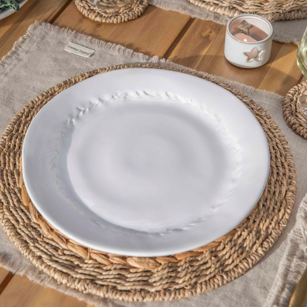 White dinner plate with leaf detailing and rattan placemat.