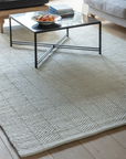 Wool rug on wooden floor with black coffee table.