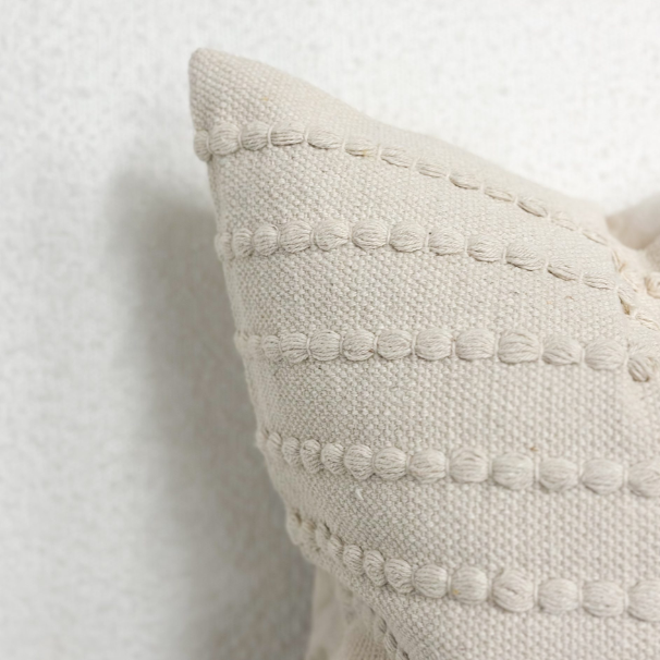 Close up of detailing on cream embroidered cushion.