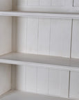 Close up of shelf in white-washed wooden display cabinet.