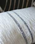 Textured Andas cream cotton cushion with slate grey stripe on a rattan chair.