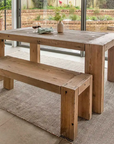 Wooden dining bench with wooden dining table in glass conservatory.