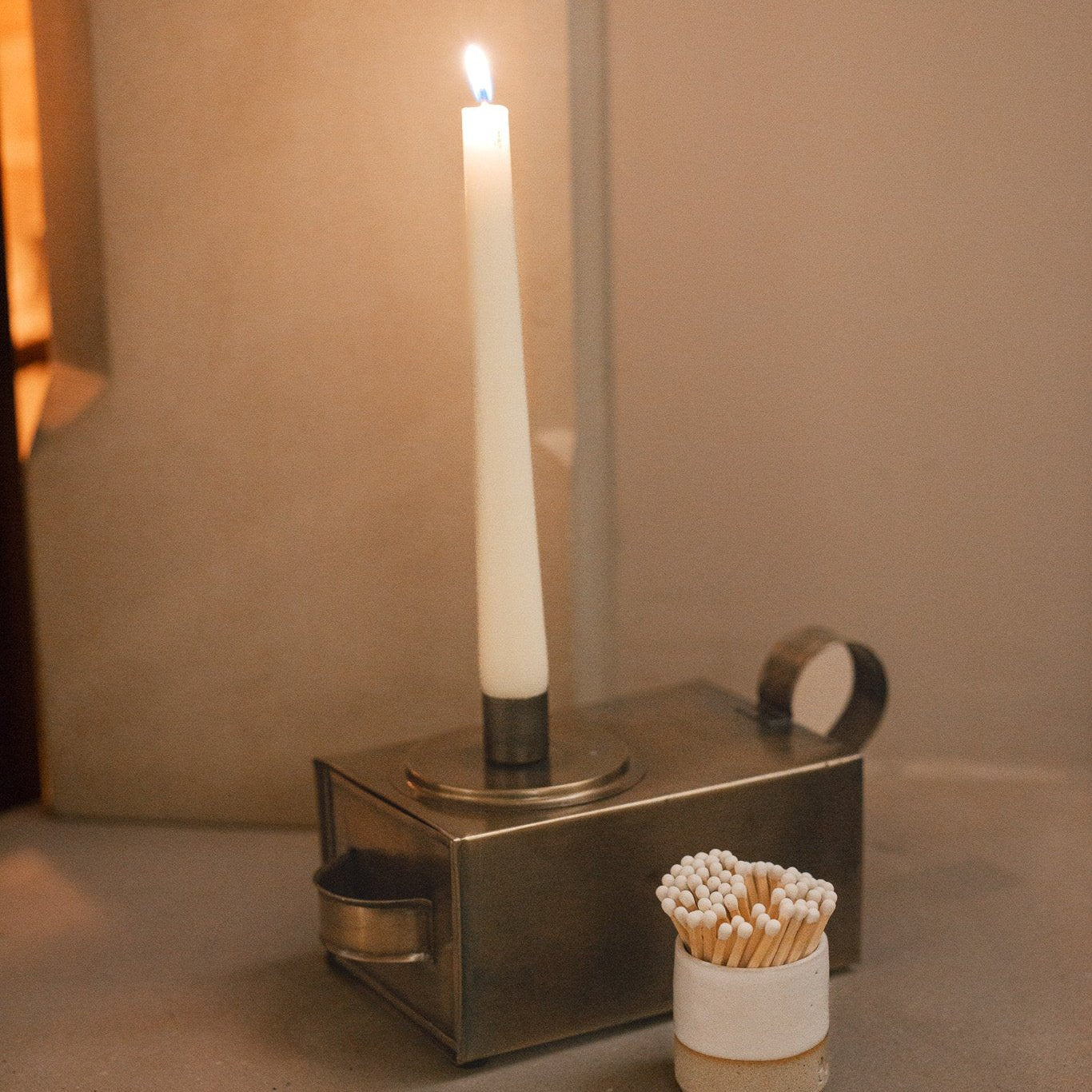 Antique Brass Candle Holder With Drawer on stone fireplace.