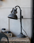 Antique black desk lamp on desk in office.