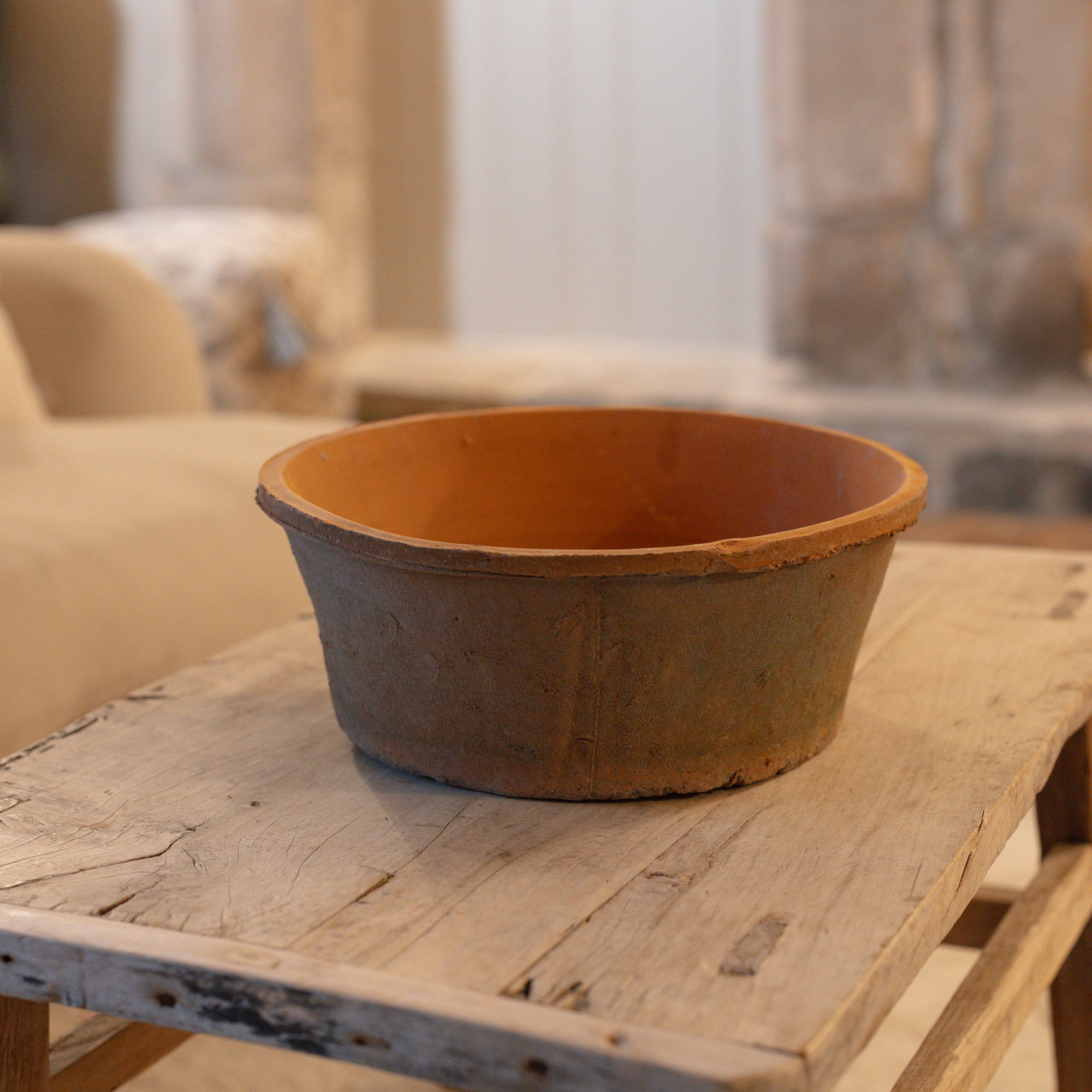 Antiqued red stone planter on wooden coffee table.