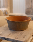 Antiqued red stone planter on wooden coffee table.