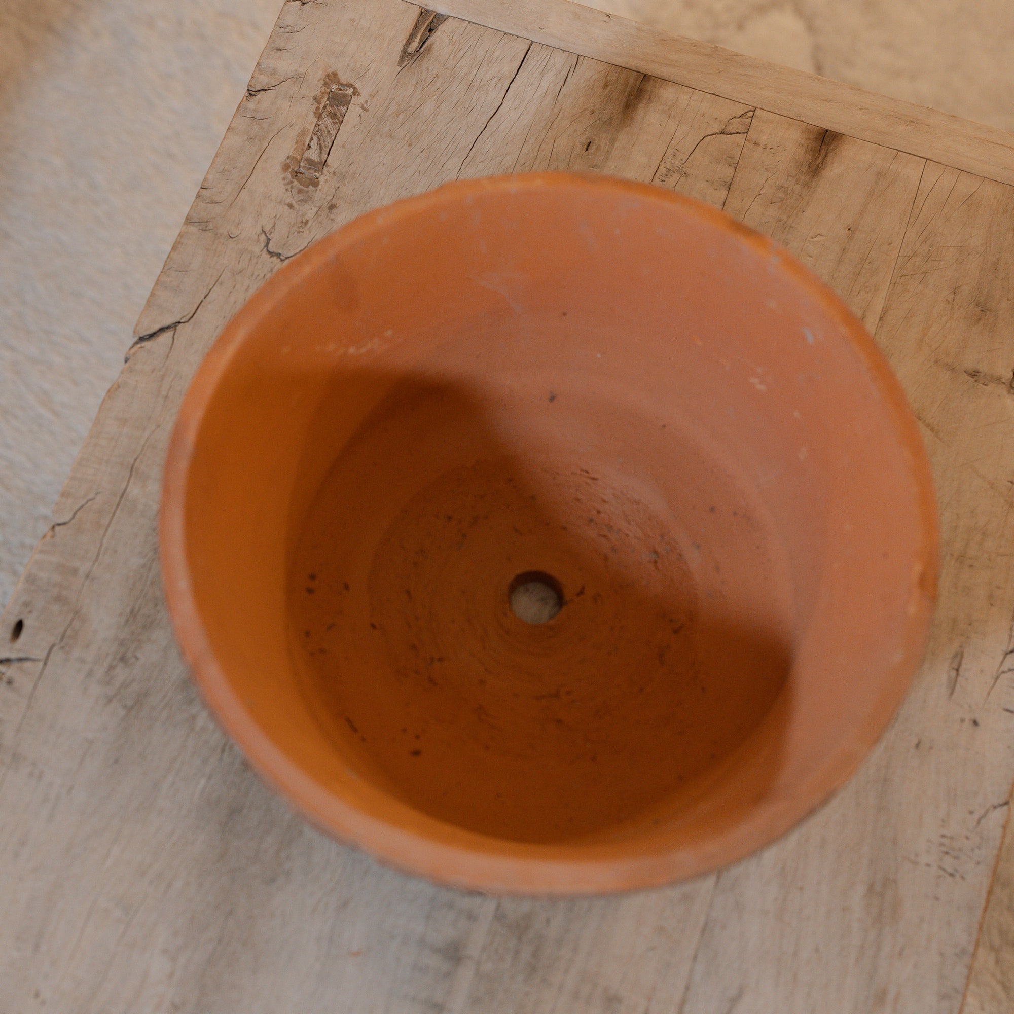 Birdseye view of Antiqued red stone planter on wooden coffee table.