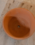 Birdseye view of Antiqued red stone planter on wooden coffee table.