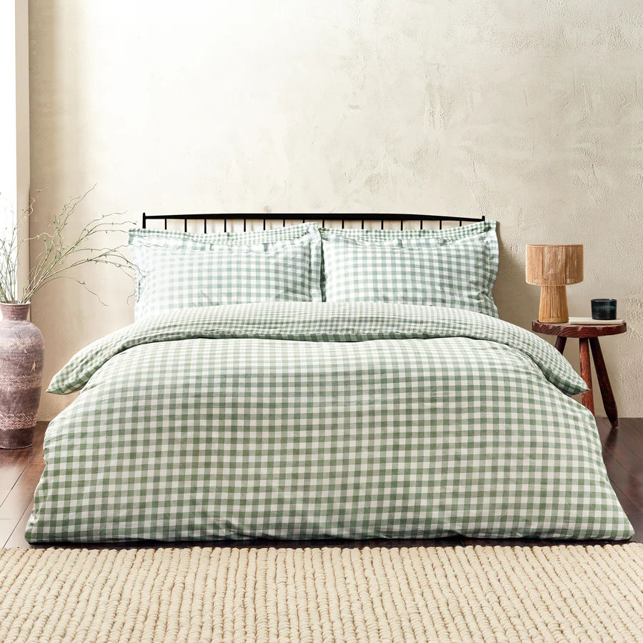 Forest green gingham bedding set on bed, with bedside table and vase.