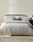 Grey gingham bedding set on bed with throw and grey cushion, with bedside table.