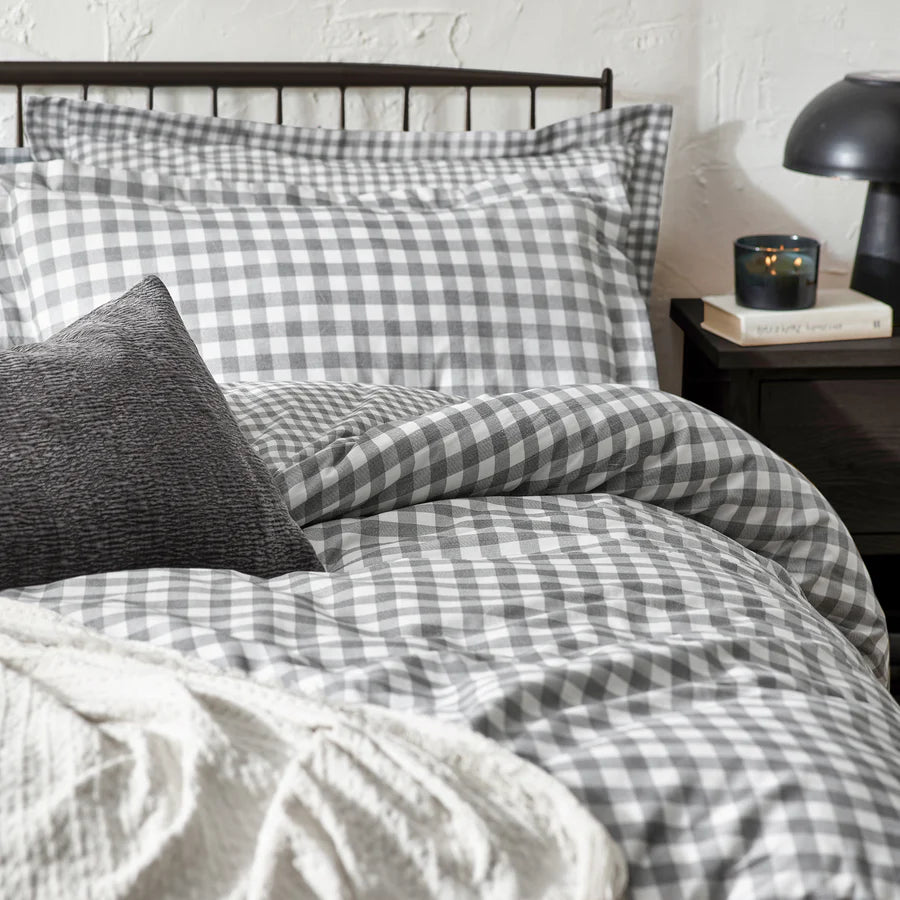 Grey gingham bedding set on bed with throw and grey cushion, with bedside table styled.