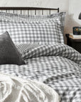 Grey gingham bedding set on bed with throw and grey cushion, with bedside table styled.