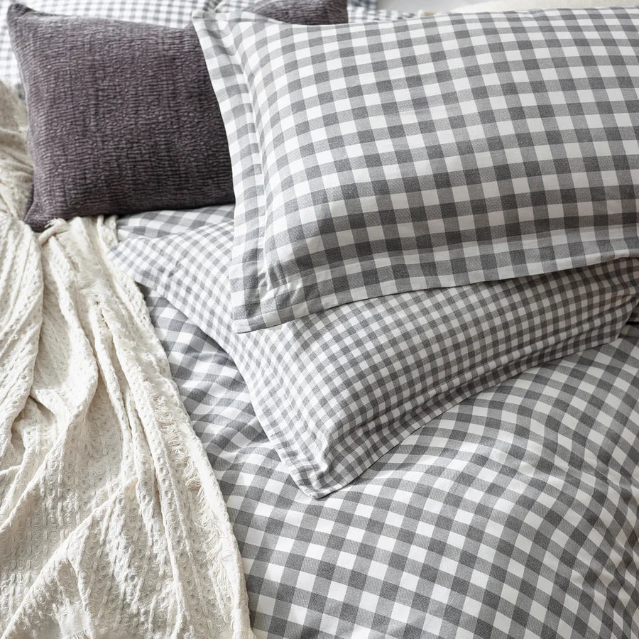 Close up of grey gingham bedding set on bed with throw and grey cushion.