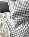 Close up of grey gingham bedding set on bed with throw and grey cushion.